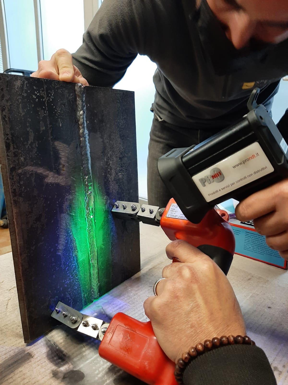 Esame di magnetoscopia con giogo elettromagnetico su saldatura di test.