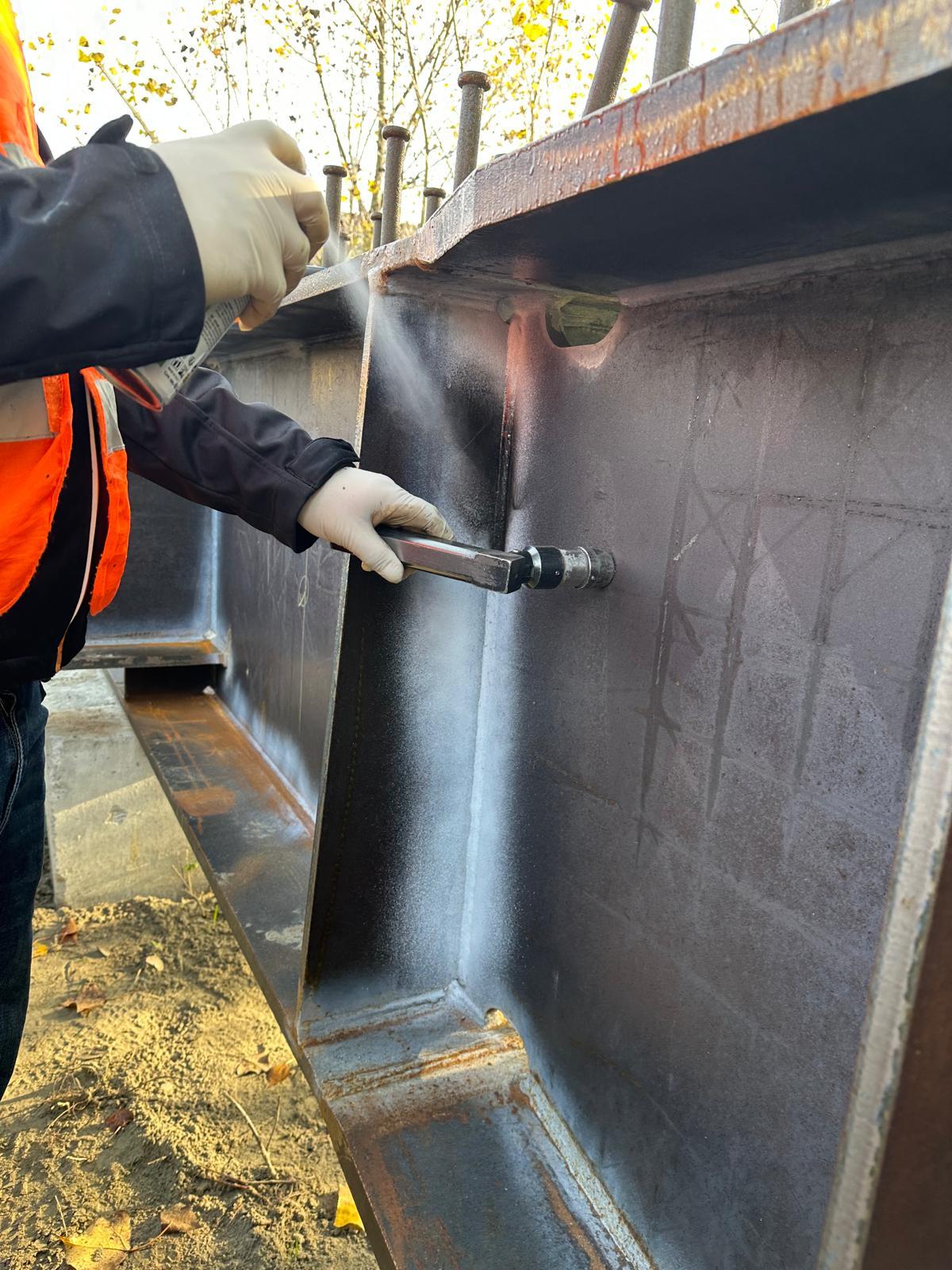 Ispezione di giunzioni saldate su carpenteria metallica in cantiere.